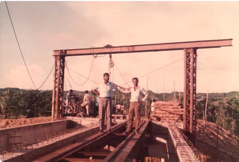 Two workers standing on a deck beneath a steel gantry frame